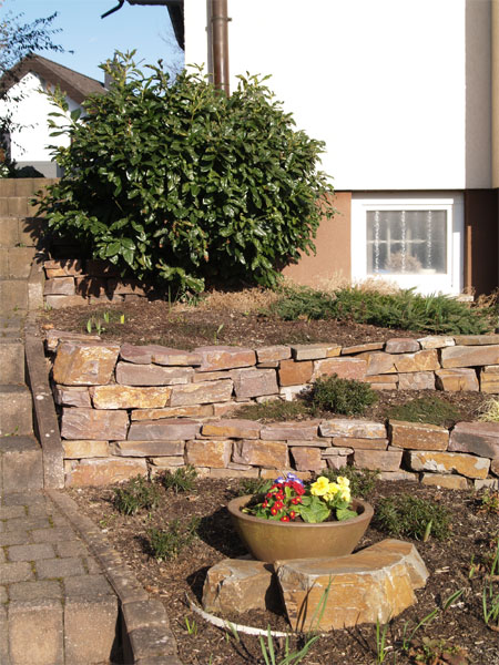 Eingangsbereich mit Moselgrauwacke terrassiert und naturnaher Bepflanzung